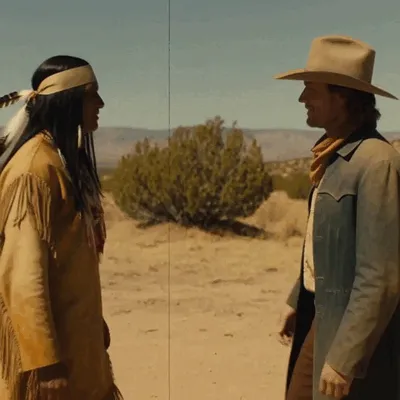 Two Western characters, a cowboy and a Native American, share an embrace.