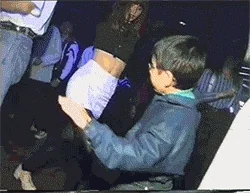 A person in a dark jacket dances in the middle of a nightclub party.