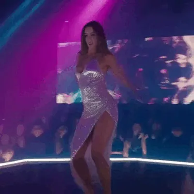 A woman in a silver dress dances under nightclub lights.