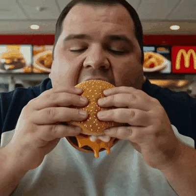 Un uomo prende un enorme morso del suo hamburger.