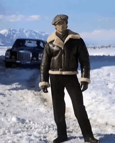 Stallone winkt in einer verschneiten Landschaft mit Bergen im Hintergrund.