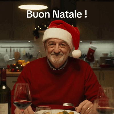Un uomo con il cappello natalizio saluta sorridendo a tavola.
