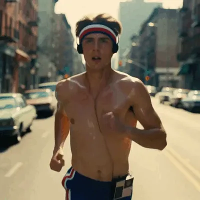 Wearing a headband and headphones, a man runs down the street.