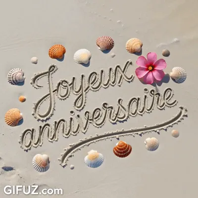 Happy Birthday is traced in the sand among seashells and a pink flower.