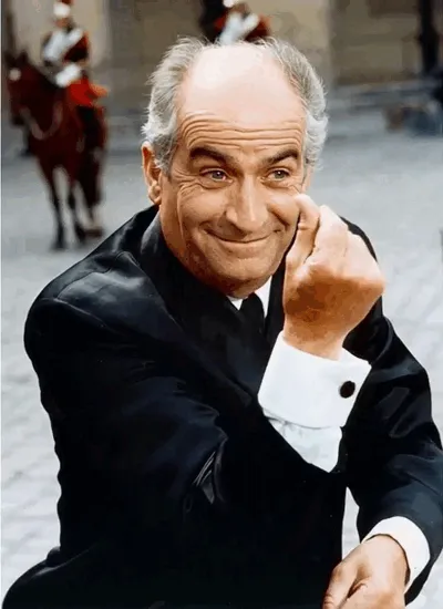 Louis de Funès sourit en frottant ses doigts pour évoquer l’argent.