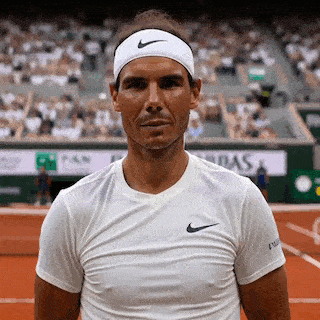 Nadal sourit et lève le pouce sur un court de tennis.