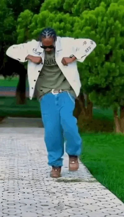 Snoop Dogg dances outdoors with a relaxed step.