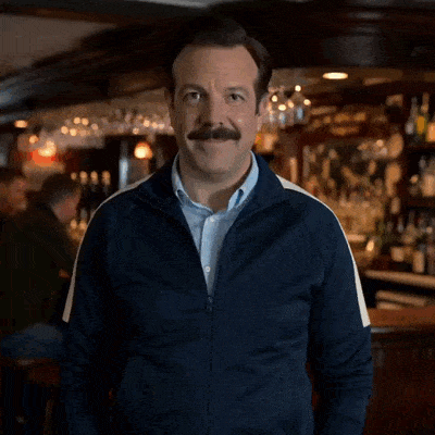 Ted Lasso sourit et fait un geste d’approbation.