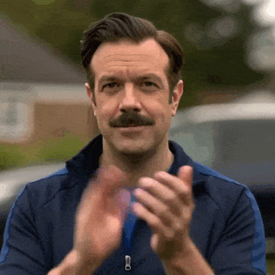 Ted Lasso applaudit pour féliciter quelqu’un.